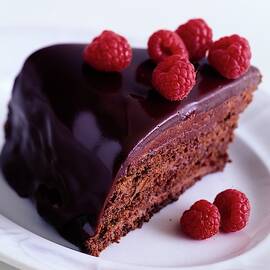 A Chocolate Pecan Cake With Raspberries On Top by Romulo Yanes