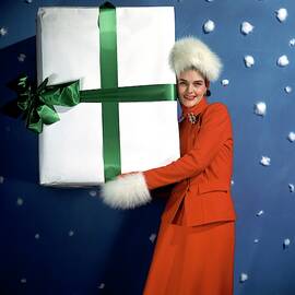 A Model Carrying A Large Wrapped Gift by John Rawlings