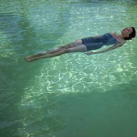 A Model Floating In A Swimming Pool by John Rawlings