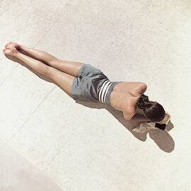 A Model Lying Down Wearing A Play Suit by John Rawlings