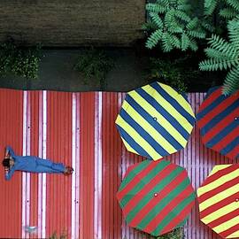 A Patio With Striped Umbrellas by James Mathews