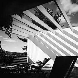 A Woman Sitting On A Reclining Chair On A Rooftop by Robert M. Damora