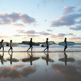 Five Surfers Walk Along Beach With Surf by Dougal Waters