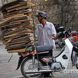 Man carrying cardboard on the back of his scooter by Sami Sarkis Photography