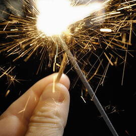 Man's hand igniting sparkler by Sami Sarkis Photography