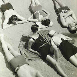 Simone Demaria And Models Sunbathing On A Beach by George Hoyningen-Huene