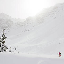 Skier Climbs Snowy Ridge Below Misty by Ascent Xmedia