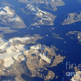 Snowy rocky islands and floating icebergs on ocean by Sami Sarkis Photography