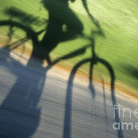 Speeding cyclist's shadow on the road by Sami Sarkis Photography