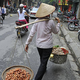Woman carrying baskets of fruits by Sami Sarkis Photography