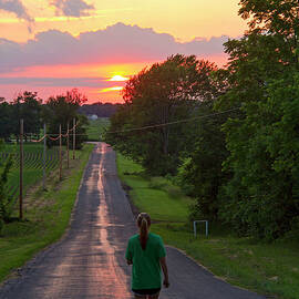 Woman Jogging On Country Road At Sunset by Matt Champlin