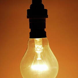 Bare hanging light bulb by Sami Sarkis Photography