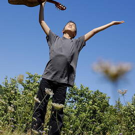 Boy standing in meadow with guitar by Sami Sarkis Photography