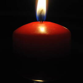 Burning candle reflected by water at night by Sami Sarkis Photography