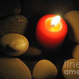 Burning candle with pebbles in water by Sami Sarkis Photography