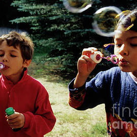 Girl and boy blowing bubble-wands by Sami Sarkis Photography