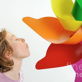 Girl blowing on a colorful windmill by Sami Sarkis Photography