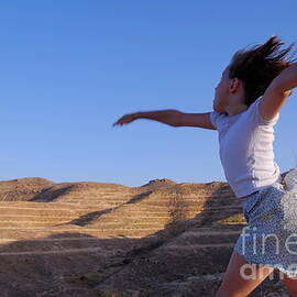Girl throwing stone in sky by Sami Sarkis Photography