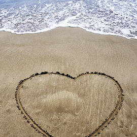 Heartshape drawn in sand on beach by Sami Sarkis Photography