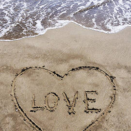 Heartshape drawn in sand on beach with Love word inside by Sami Sarkis Photography