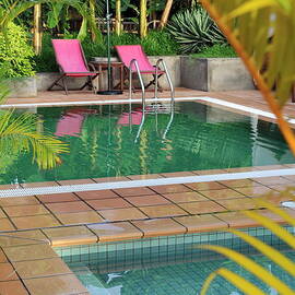 Seats and umbrella by swimming pool by Sami Sarkis Photography