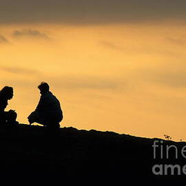 Silhouette of a squatting couple at sunset by Sami Sarkis Photography