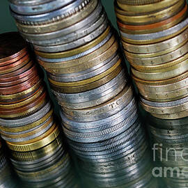 Stacks of various currency coins on reflective surface by Sami Sarkis Photography