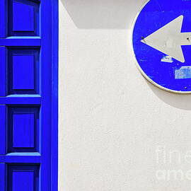 Street arrow sign and blue door on white wall by Sami Sarkis Photography