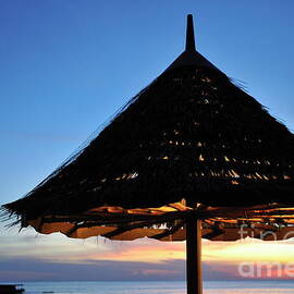 Thatched parasol on the beach at sunset by Sami Sarkis Photography