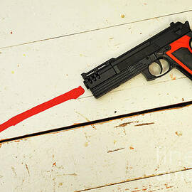 Toy gun on floor with red paint by Sami Sarkis Photography