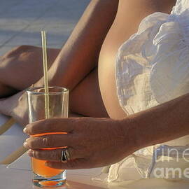 Woman holding cocktail glass while sunbathing by Sami Sarkis Photography