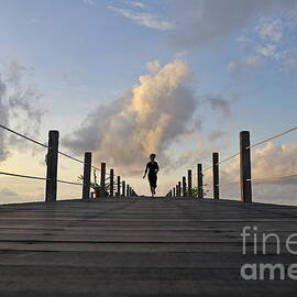 Woman running on wooden jetty at sunrise by Sami Sarkis Photography