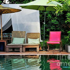 Wooden seats and umbrellas reflected in pool by Sami Sarkis Photography