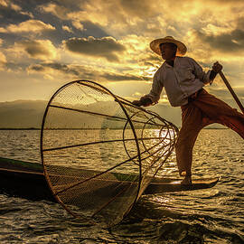 Burmese fisherman on a bamboo boat at sunrise by Miroslav Liska