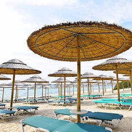 Beach umbrellas and chairs on sandy seashore by Elena Elisseeva