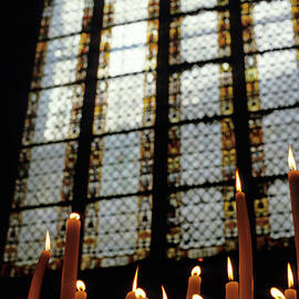 Candles burning in front of a stained glass window in the Auch Cathedral by Sami Sarkis Photography