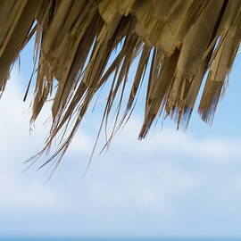 Edge of a sun umbrella straw with blue waters in the background by Sami Sarkis Photography