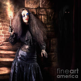 Female jester walking inside dark castle stairwell by Jorgo Photography