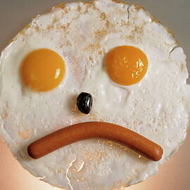 Fried breakfast of eggs and sausage made into a frowning face by Sami Sarkis Photography