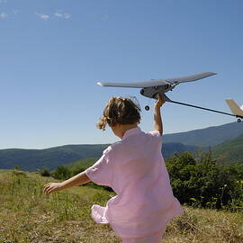 Girl flying model plane in field by Sami Sarkis Photography