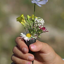 Girl holding flowers in a rifle cartridge by Sami Sarkis Photography