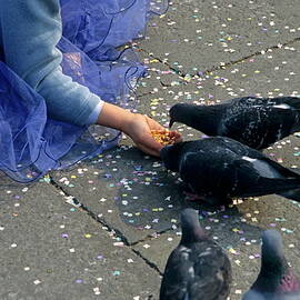 Girl holding her hands out to feed pigeons by Sami Sarkis Photography