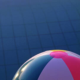 Inflatable beach ball floating in a swimming pool by Sami Sarkis Photography