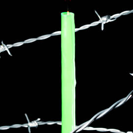 Lit candle surrounded by barbed wire by Sami Sarkis Photography