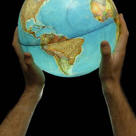 Man holding illuminated Earth globe by Sami Sarkis Photography