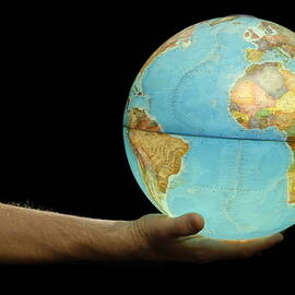 Man offering illuminated Earth globe by Sami Sarkis Photography