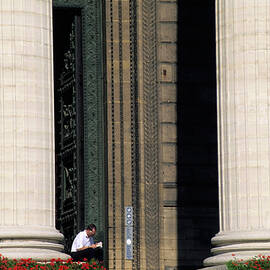 Man reading a book beside the columns of La Madeleine church in Paris by Sami Sarkis Photography