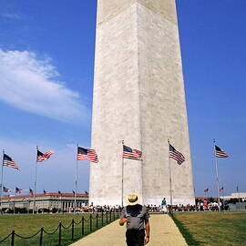 Man walking down a footpath with the Washington Monument in the background by Sami Sarkis Photography