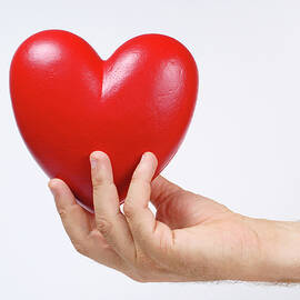 Man's hand holding heart-shaped object by Sami Sarkis Photography