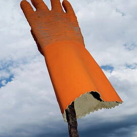 Orange rubber glove on a wooden post against a cloudy sky by Sami Sarkis Photography